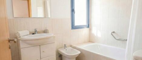 A modern bathroom with a sink, bidet, toilet, and bathtub.