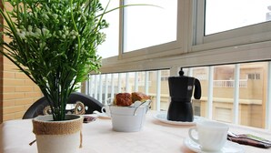 A table with a potted plant, a cup of coffee, and a teapot.