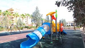 A playground with a blue slide, climbing structures, and a fenced area.