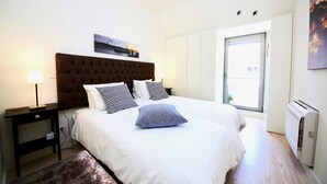 Een slaapkamer met een groot bed, een nachtkastje, een lamp, een raam met uitzicht en een wandairconditioner.