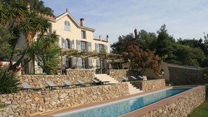 A poolside area with a stone wall, a pool, and a building with multiple windows and a balcony.