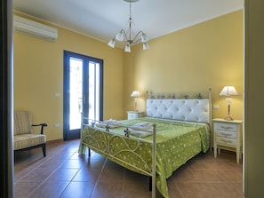A bedroom with a bed, two bedside tables, a chair, and a door.