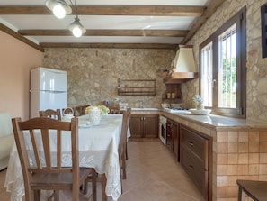 A kitchen with stone walls, wooden cabinets, and a dining area with a table set for four.