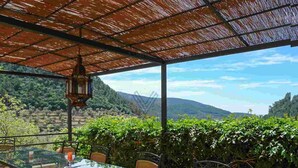 Mesa de vidrio con sillas en un entorno exterior con vistas a colinas y árboles.