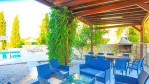 An outdoor patio with wicker furniture, a stone wall, and a barbecue grill. - Villa Georgios Rafaela: Secluded, pool, Wifi, A/C, sleeps 10 (Goudi Polis)