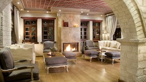 Un salon chaleureux avec une cheminée, des fauteuils confortables et une arche en pierre.