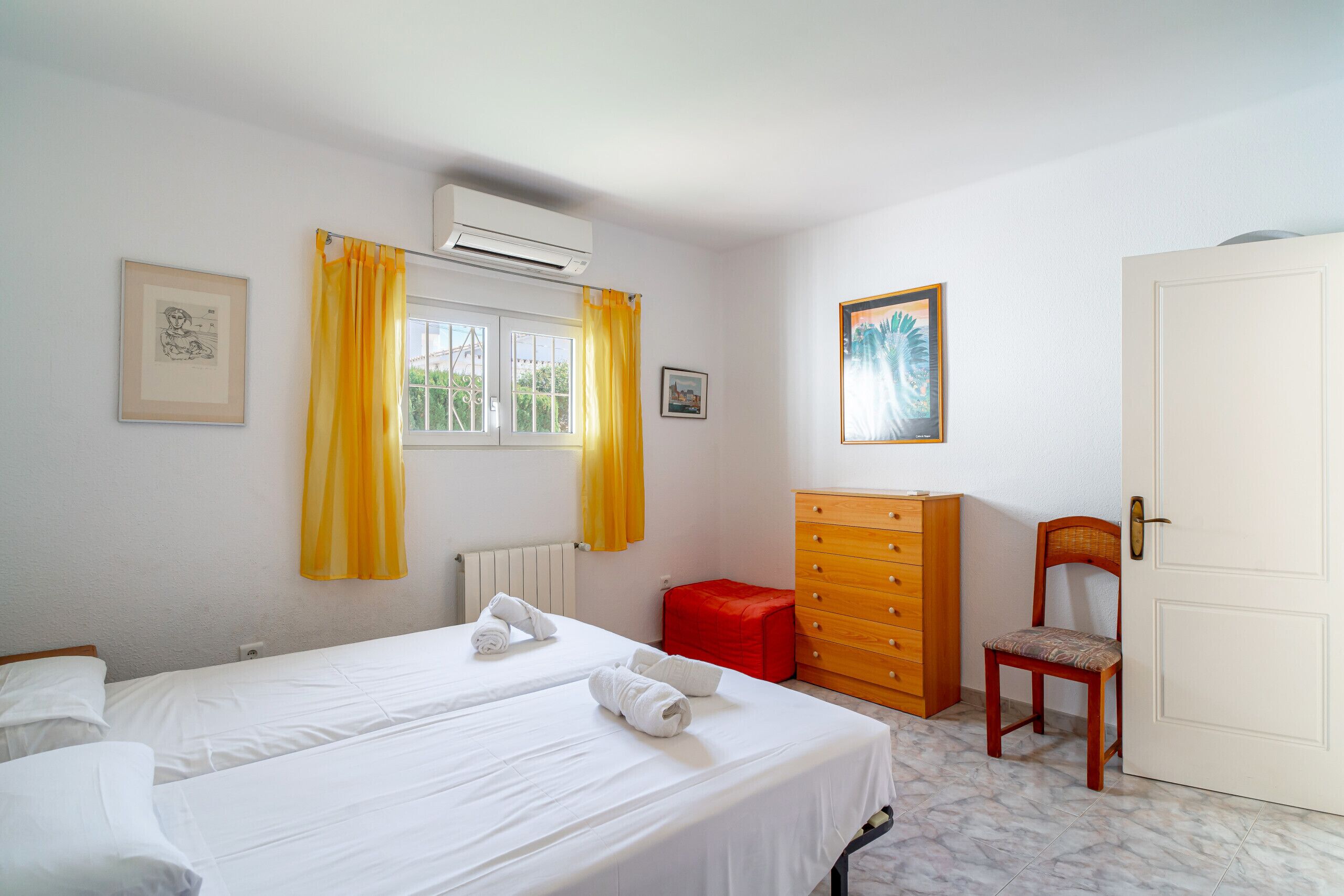 A hotel room with two beds, a wooden dresser, a chair, and a door.