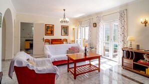 A living room with a red sofa, a wooden coffee table, a white couch, and a chandelier. - Villa Sevilla Private Pool by Casasol (Nerja)
