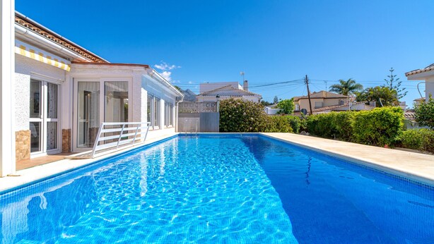 A swimming pool with clear blue water, surrounded by a white building with large windows and a balcony. - Villa Sevilla Private Pool by Casasol (Nerja)