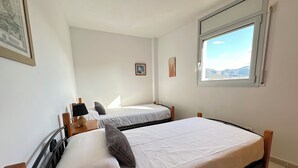 Un dormitori amb dos llits, una finestra amb vista i un quadre al mur.