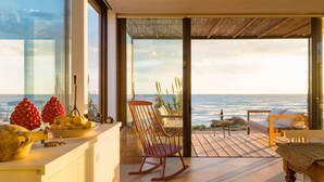 Cozinha moderna com vista para o oceano, uma cadeira de balanço e um espaço de jantar com mesa e cadeiras.
