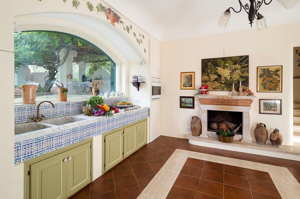 A kitchen with a large window, a fireplace, and tiled backsplash.