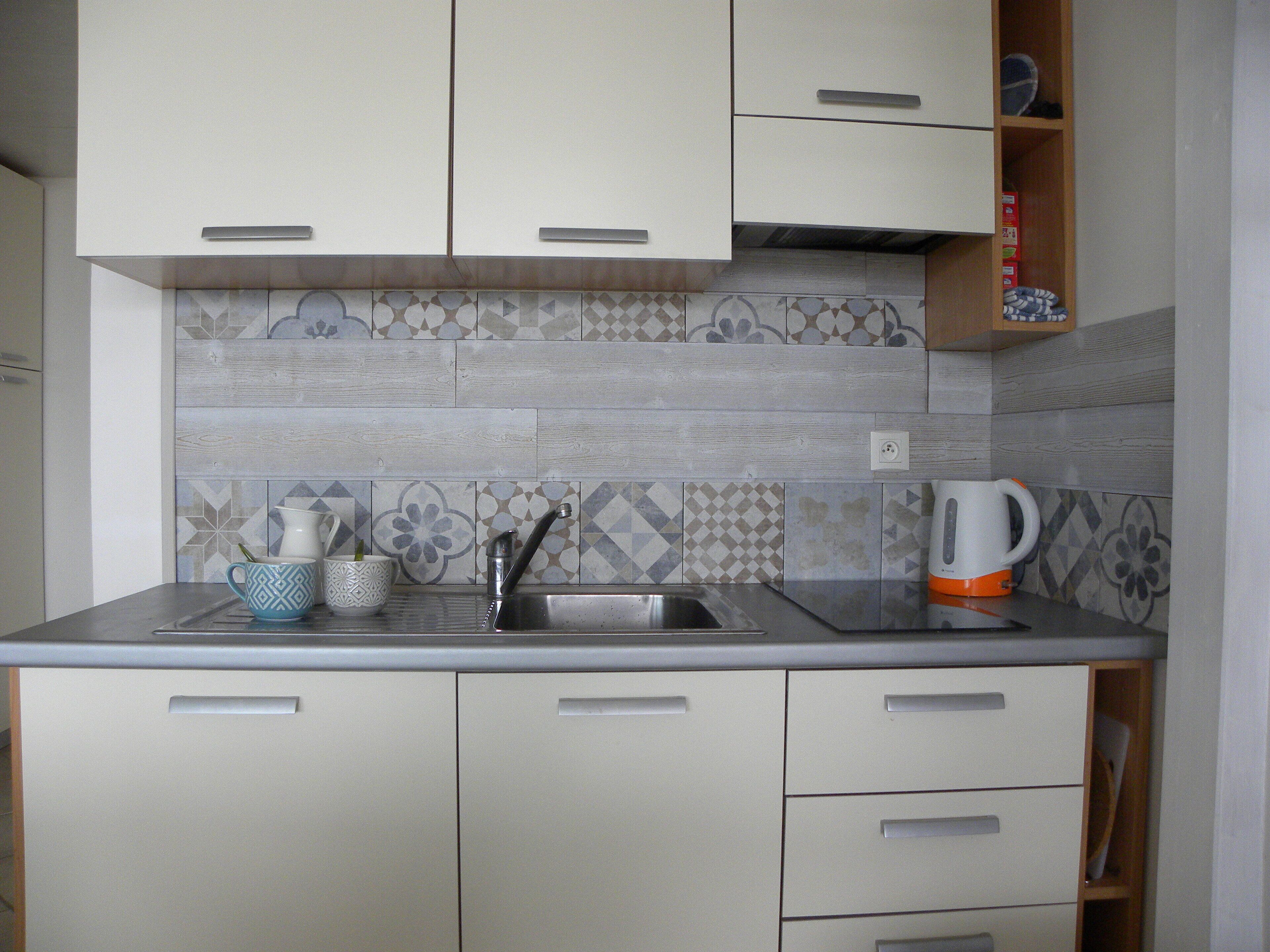 A kitchen with a tiled backsplash, a sink, and cabinets.