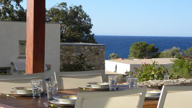 Mesa posta para refeição com vista para o mar.