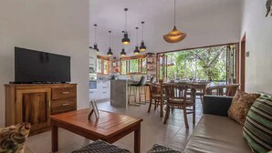 A modern living room with a TV, wooden furniture, and a dining area with chairs and a table. - Lovina luxury pool villa at a magnificent location! (Lovina)