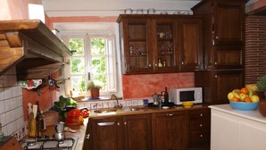 Una cocina con armarios de madera, estufa, lavaplatos y ventana con vistas a zonas verdes.