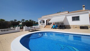A swimming pool with a white deck, a covered patio with outdoor furniture, and a white building with a tiled roof. - Finca in quiet area with private pool (Catral Alicante)