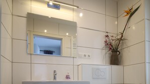 Une salle de bain moderne avec un meuble-lavabo blanc, des toilettes et un miroir.