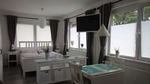 Une chambre à coucher avec un lit, une table de chevet, une télévision et une fenêtre avec des rideaux.
