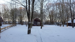 Un parque cubierto de nieve con una pequeña cabaña de madera y una cerca de madera.