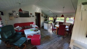 Un espacio habitable compacto con un sofá rojo, una mesa de comedor con sillas, una zona de cocina y una pequeña isla.