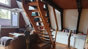 Ein Loft-Zimmer mit Holztreppe, einer Couch und einer Heizung.