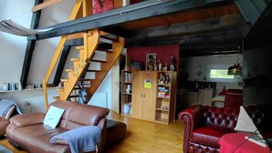 Ein Loft mit einer Holztreppe, einem roten Leder-Sofa, einem braunen Leder-Sofa und Holzboden.