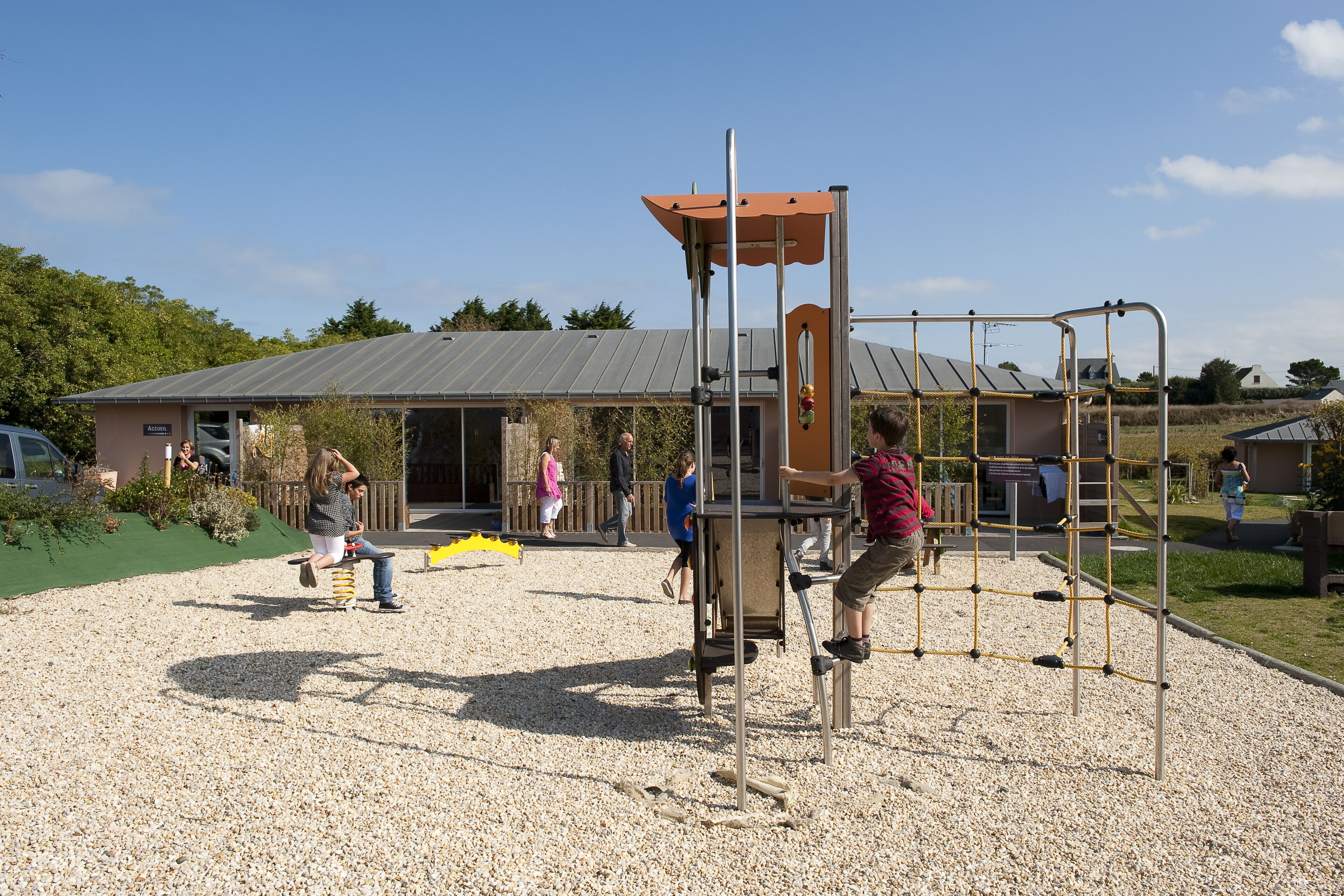 An outdoor playground with climbing structures and a covered seating area.