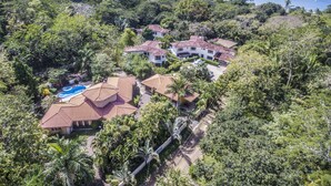 A coastal residential area with multiple houses, a swimming pool, and lush greenery.