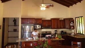A spacious kitchen with wooden cabinets, a central island, and a ceiling fan.
