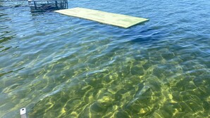 A clear view of a swimming pool with a wooden deck and a floating platform.