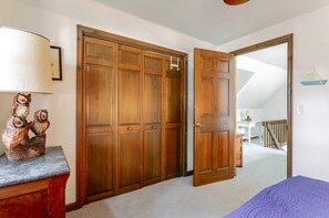 A bedroom with a bed, a wooden wardrobe, a desk, and a chair.