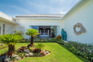 Ein modernes Haus mit gepflegtem Garten, einem Ziegeldach und einem großen Wandkunstwerk.