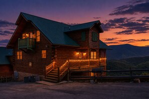 Une cabane en bois dotée d’un balcon, d’un escalier et offrant une vue sur les montagnes.