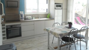 Een kleine keuken met een eethoek, een magnetron, een koffiezetapparaat en een spoelbak.