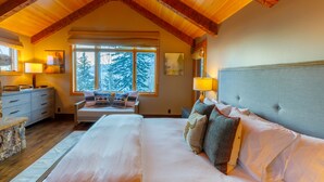 A bedroom with a large bed, a wooden ceiling, and a window with a view of trees. -  5 Bed/5.5 Bath Ski-in Ski-out Lodge on Granite Ridge (Jackson)