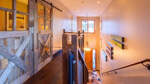 A wooden staircase with a railing, a chandelier, and a door with glass panels. -  5 Bed/5.5 Bath Ski-in Ski-out Lodge on Granite Ridge (Jackson)