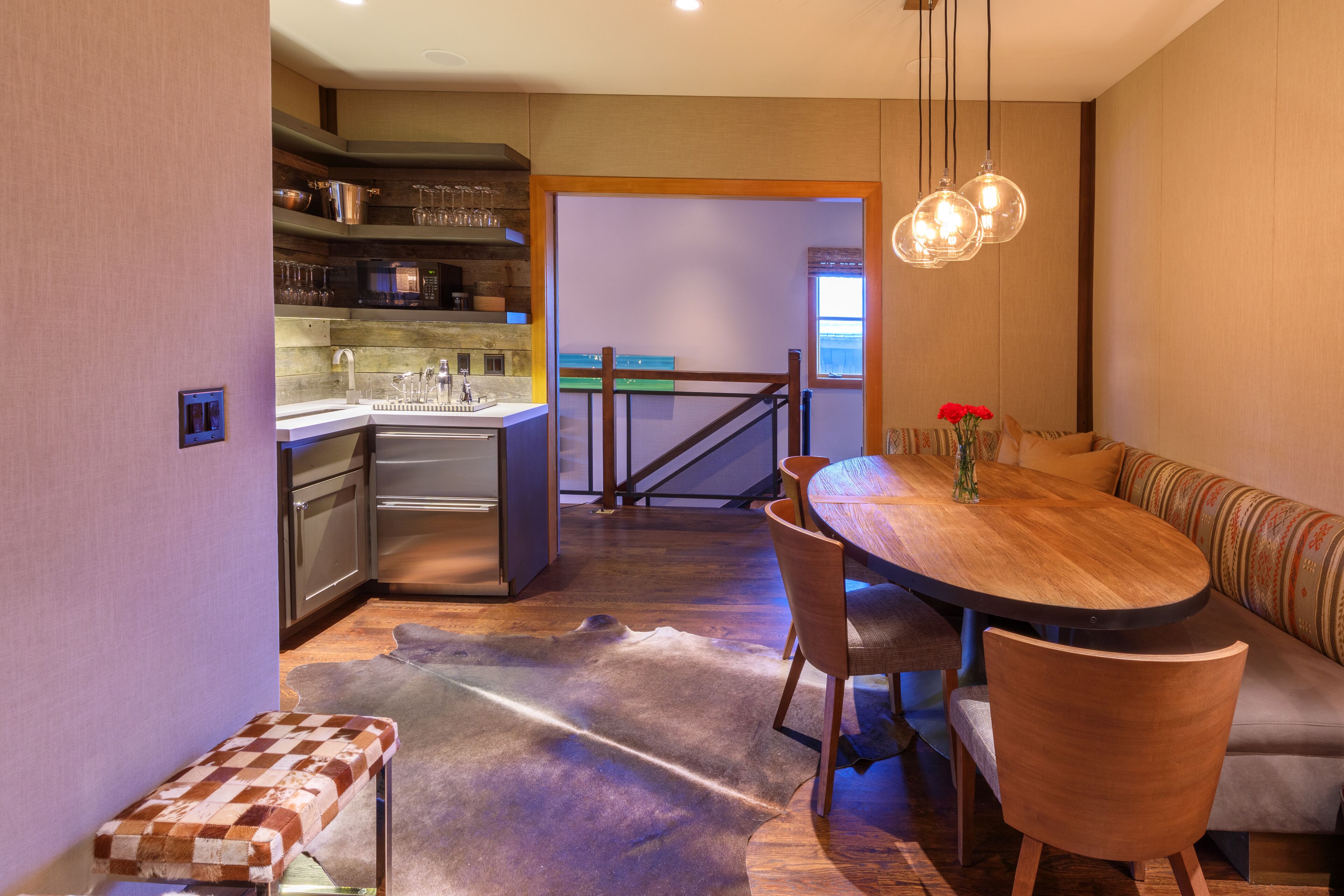 A modern kitchen with a dining area, a bench, and a staircase leading to another room.