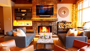 A cozy living room with a stone fireplace, comfortable sofas, a flat-screen TV, and a well-stocked bar area. -  5 Bed/5.5 Bath Ski-in Ski-out Lodge on Granite Ridge (Jackson)