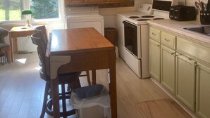 A kitchen with wooden cabinets, a dining table with chairs, and a window with curtains. - Charming 4 Bedroom Country House - 10 km from Summerside -  (Miscouche)