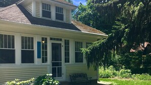 A two-story house with a front porch, a stone pathway, and a potted plant. - 1 block to the beach, easy stroll to town.Screened porch, private yard, fire pit (Union Pier)