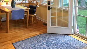A dining area with a wooden table, chairs, a vase with flowers, and a blue rug. - 1 block to the beach, easy stroll to town.Screened porch, private yard, fire pit (Union Pier)