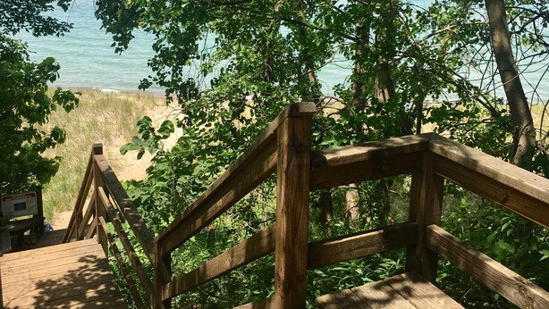 A wooden staircase leading to a beach, surrounded by trees and a clear view of the sea. - 1 block to the beach, easy stroll to town.Screened porch, private yard, fire pit (Union Pier)