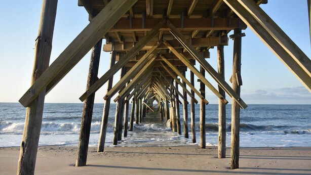 A wooden pier extending into the ocean with a clear view of the sea.