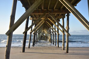 A wooden pier extending into the ocean with a clear view of the sea.