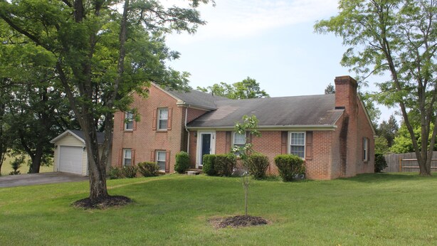 A two-story brick house with a front yard, a garage, and a chimney.
