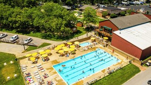 An aerial view of a swimming pool area with multiple lanes, sun loungers, and umbrellas.