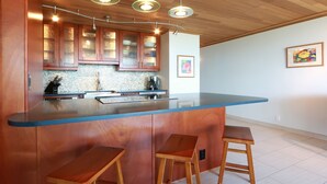 Een moderne keuken met houten kastjes, een blauw aanrecht en drie houten krukken.