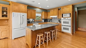 Una cocina moderna con armarios de madera, encimera de granito y una isla integrada con taburetes.