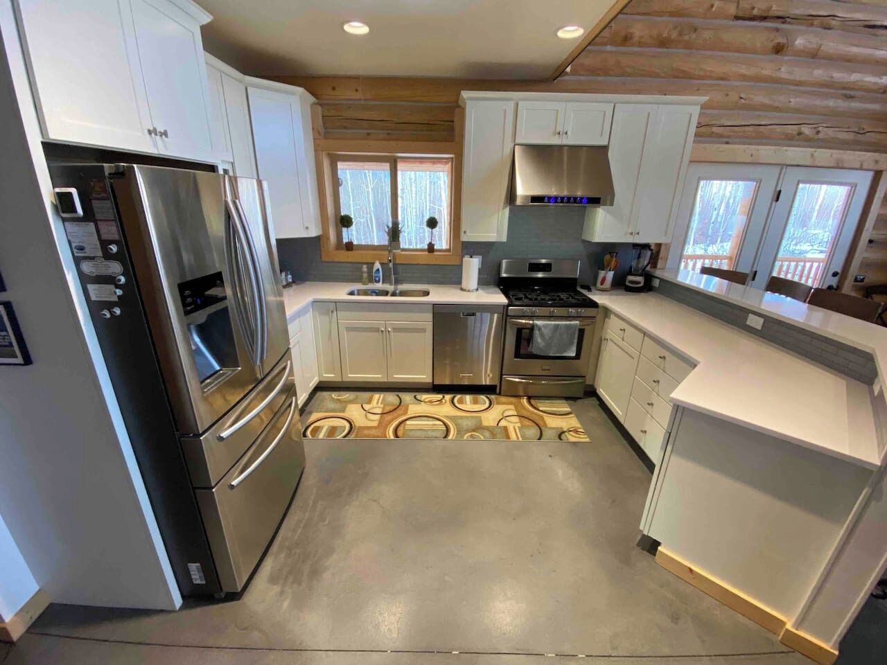 A modern kitchen with stainless steel appliances, white cabinetry, and a patterned floor.